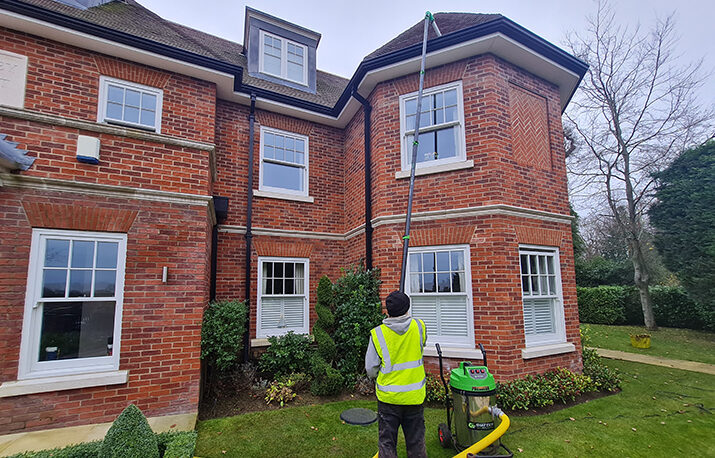 man clearing gutters with pole